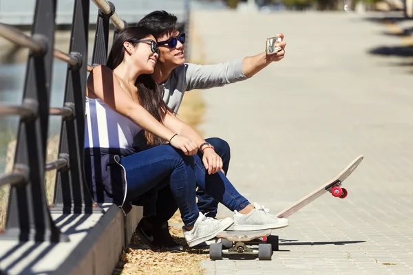 Two skaters using mobile phone in the street. — Stock Photo, Image