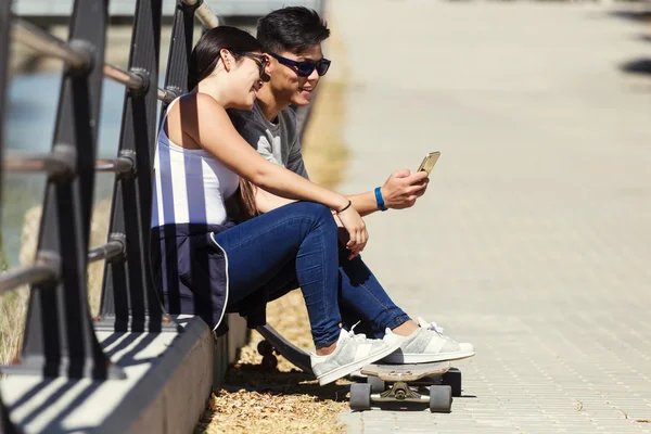 Dva bruslaře pomocí mobilního telefonu na ulici. — Stock fotografie