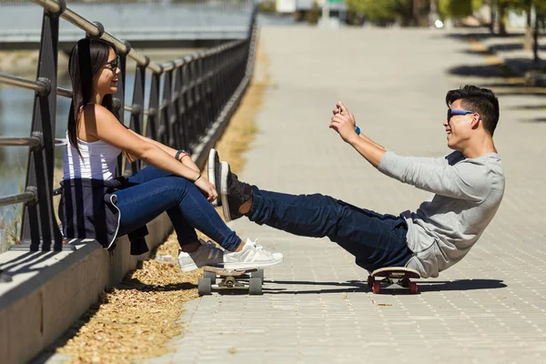 Dois patinadores usando telefone celular na rua . — Fotografia de Stock
