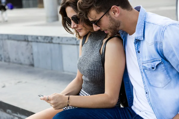 Feliz jovem casal usando telefone celular na rua . — Fotografia de Stock