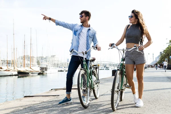 Feliz joven pareja ciclismo en la ciudad . — Foto de Stock