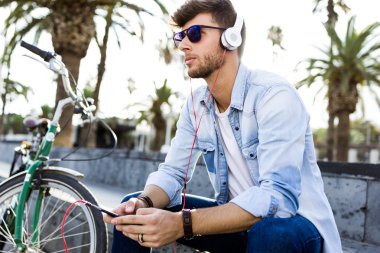 Yakışıklı genç adam sokakta müzik dinlemek.