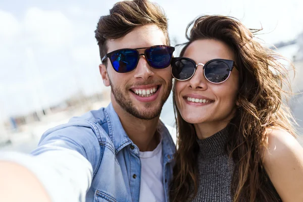 Joyeux jeune couple utilisant un téléphone portable dans la rue . — Photo