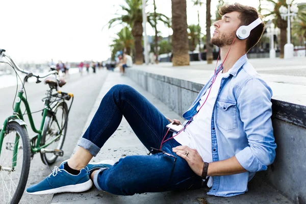 Красивый молодой человек слушает музыку на улице . — стоковое фото