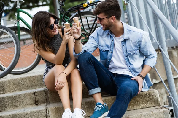 Glückliches junges Paar isst Eis auf der Straße. — Stockfoto