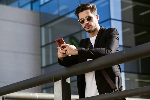 Stilig ung man använder sin mobiltelefon på gatan. — Stockfoto