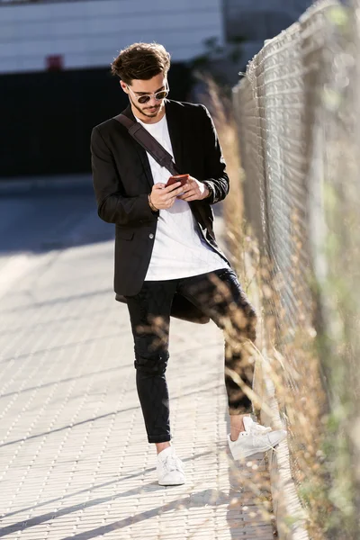 Knappe jongeman met behulp van zijn mobiele telefoon in de straat. — Stockfoto