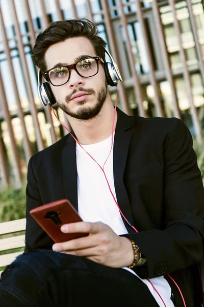 Knappe jongeman, luisteren naar muziek met mobiele telefoon in de straat. — Stockfoto