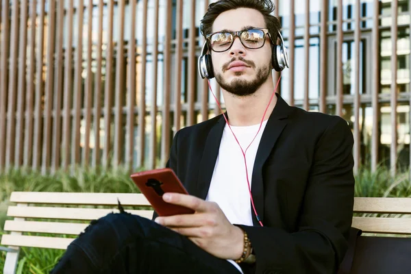 Красивый молодой человек слушает музыку с мобильного телефона на улице . — стоковое фото