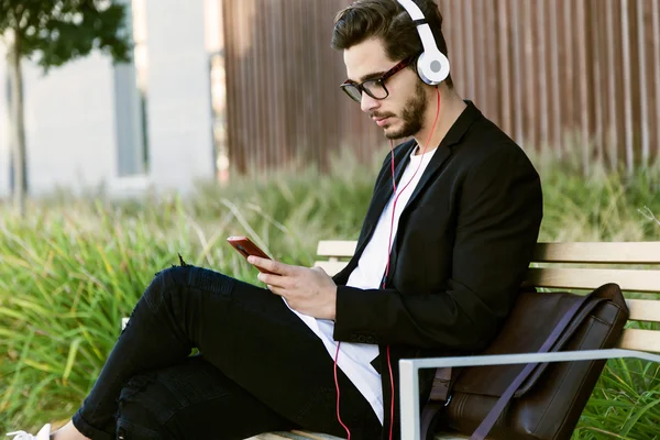 Joven guapo escuchando música con teléfono móvil en la calle . — Foto de Stock