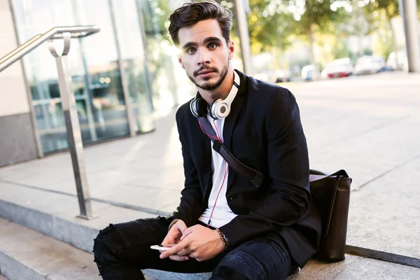 Knappe jongeman met behulp van zijn mobiele telefoon in de straat. — Stockfoto