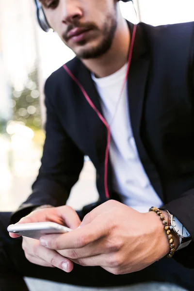 Knappe jongeman, luisteren naar muziek met mobiele telefoon in de straat. — Stockfoto