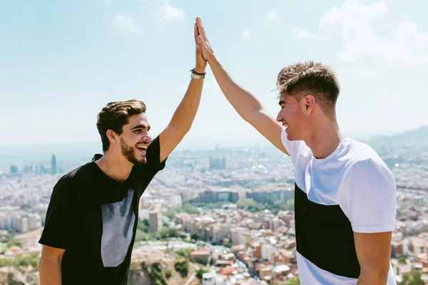 Twee jonge mannen kijken naar de standpunten vormen de top van een berg. — Stockfoto