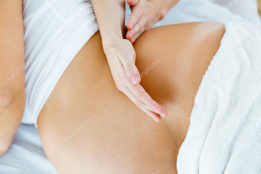 Beautiful pregnant woman having a massage in spa.