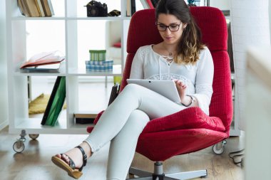 Güzel genç kadın onun dijital tablet evde kullanma.