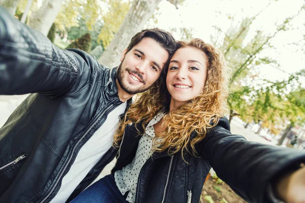 Beautiful young couple using they mobile phone in the park. — Stock Photo, Image