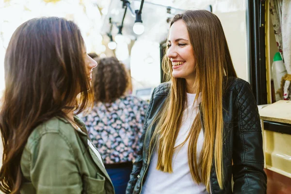 Dvě mladé ženy na návštěvě jíst trh na ulici. — Stock fotografie