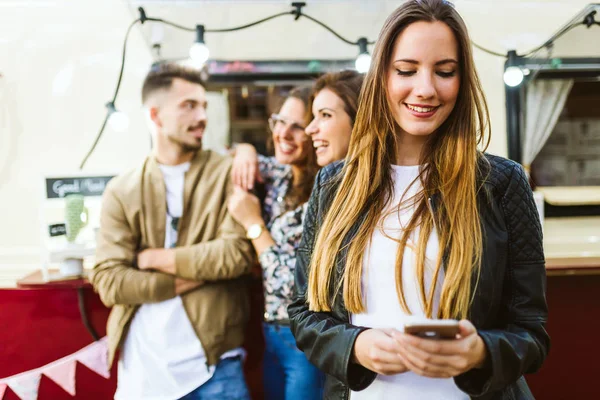 Schöne junge Frau mit ihren Freunden mit dem Handy. — Stockfoto