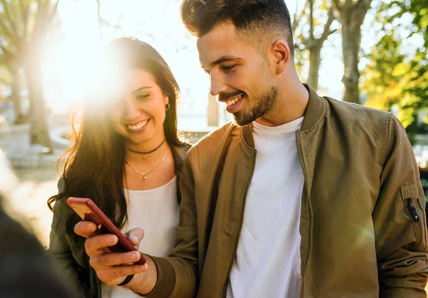 Schönes junges Paar benutzt sein Handy auf der Straße. — Stockfoto