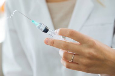 Kadın doktor büyük bir kas içi şırınga tutarak.