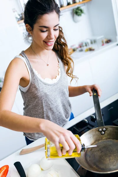 Молода жінка вливає олію в сковороду . — стокове фото