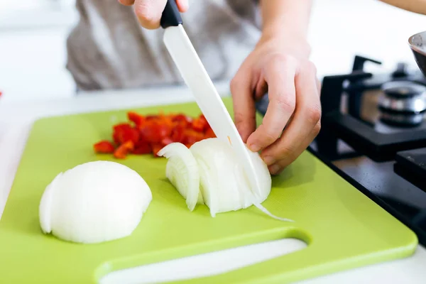 Happy young woman cutting fresh vegetables in kitchen — Stock Photo, Image