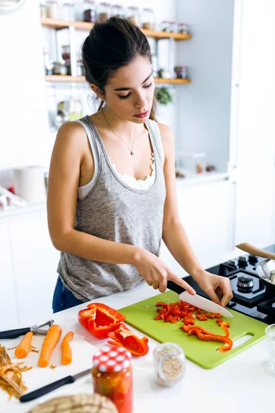 Щаслива молода жінка, що ріже свіжі овочі на кухні — стокове фото