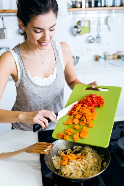 Молода жінка смажить овочі на сковороді . — стокове фото