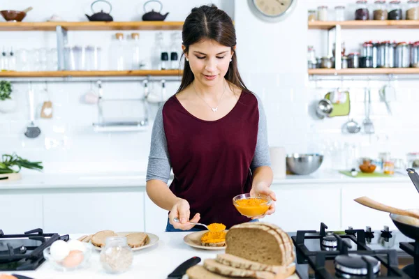 부엌에서 으깬 야채 토스트를 준비 하는 아름 다운 젊은 여자. — 스톡 사진