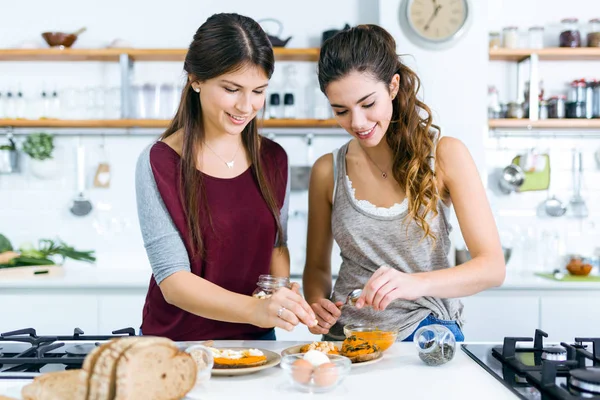 Deux belles femmes préparant des toasts avec de la purée de légumes, des œufs et des graines . — Photo
