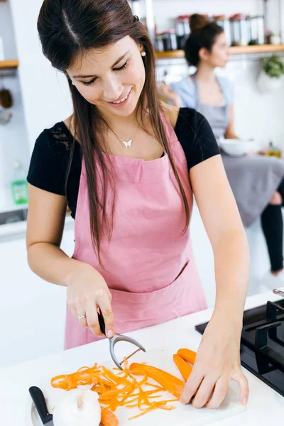Красивая молодая женщина режет морковь на кухне . — стоковое фото