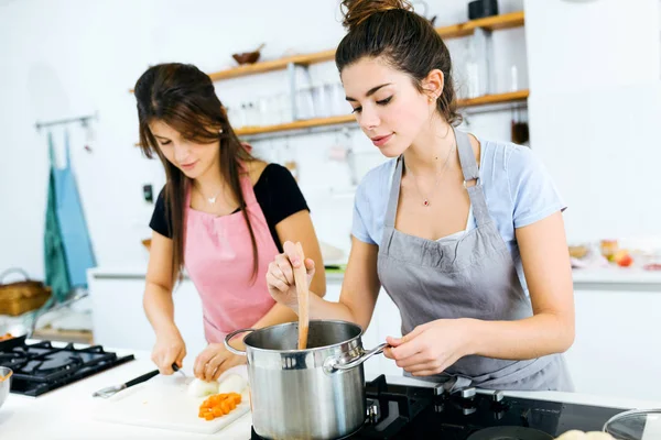 Дві красиві жінки ріжуть і готують свіжі овочі на кухні . — стокове фото