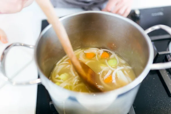 Beautiful young woman cooking soup with vegetables at home. — Stock Photo, Image