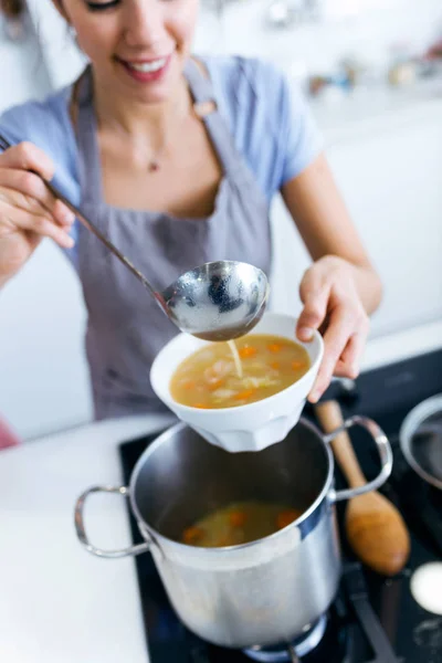 Jonge vrouw serveren groentesoep in de keuken. — Stockfoto