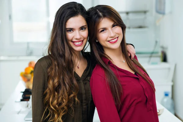 Dos hermosas mujeres jóvenes mirando a la cámara en la cocina . — Foto de Stock