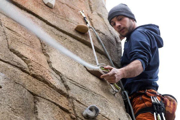 Handsome young man climbing natural rocky wall.