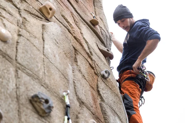 Handsome young man climbing natural rocky wall.