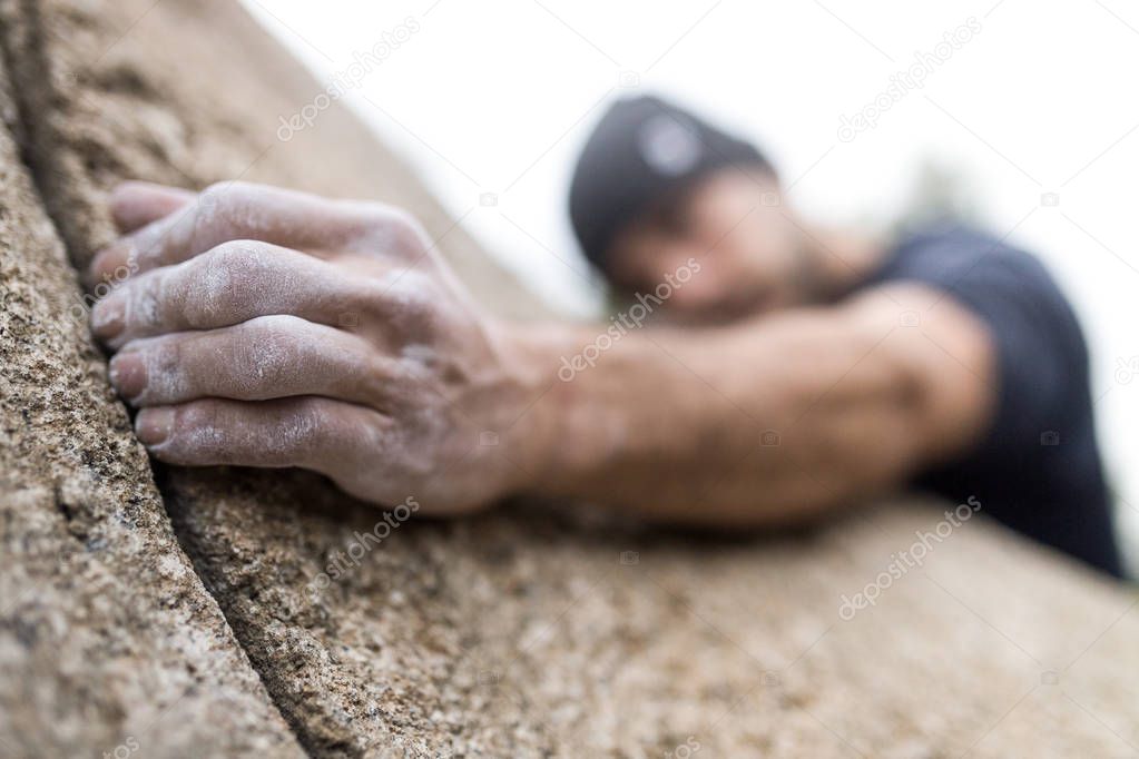 Handsome young man climbing natural rocky wall.