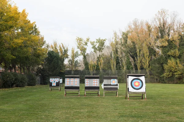 Outdoor archery targets on grass field surrounded by forest.