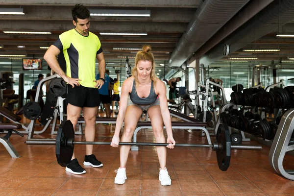 Jeune couple sportif faisant de l'exercice musculaire en salle de gym . — Photo