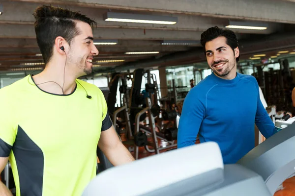 Dos jóvenes guapos haciendo entrenamiento cardiovascular en el gimnasio . — Foto de Stock