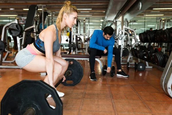 Jeune couple sportif faisant de l'exercice musculaire en salle de gym . — Photo