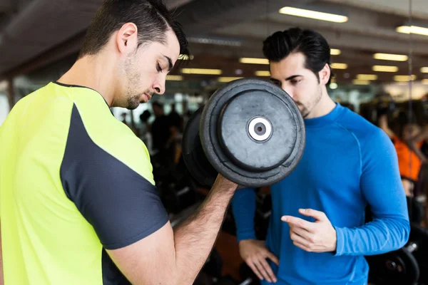 Dos jóvenes guapos haciendo ejercicio muscular en el gimnasio . — Foto de Stock