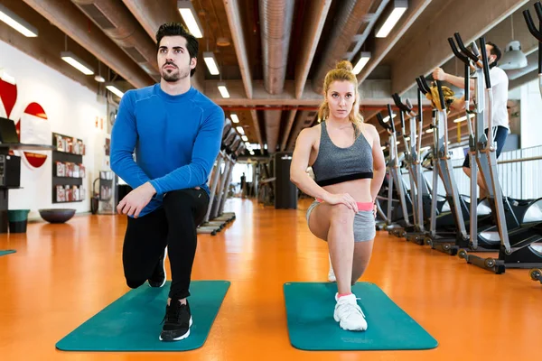 Jeune couple sportif faisant de l'exercice musculaire en salle de gym . — Photo