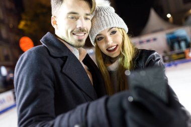 Güzel genç bir çift kullanarak onlar buz pateni cep telefonu