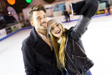 Güzel genç bir çift kullanarak onlar buz pateni cep telefonu