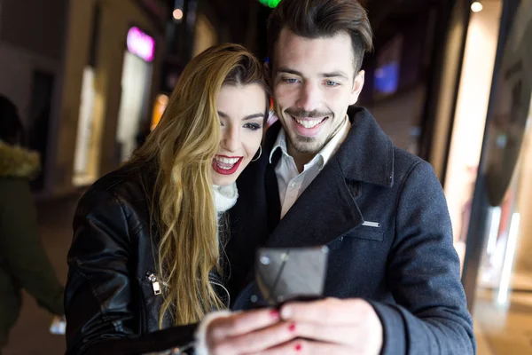 Hermosa pareja joven utilizando el teléfono móvil en la calle . — Foto de Stock