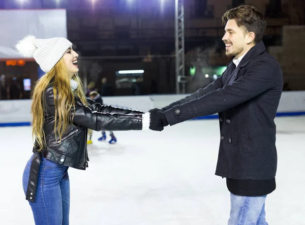 Hermosa pareja joven patinaje sobre hielo en pista al aire libre . — Foto de Stock