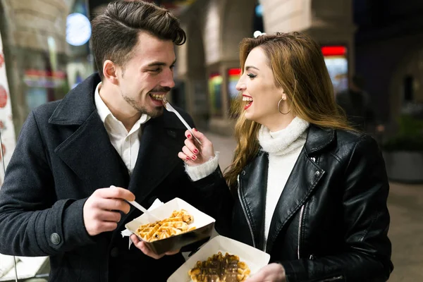 Belo jovem casal comendo waffles na rua . — Fotografia de Stock