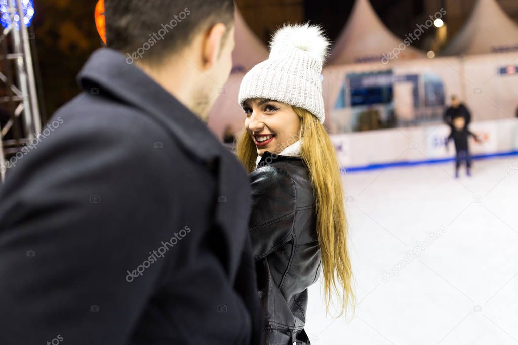 Beautiful young couple in love on the ice skating outdoors